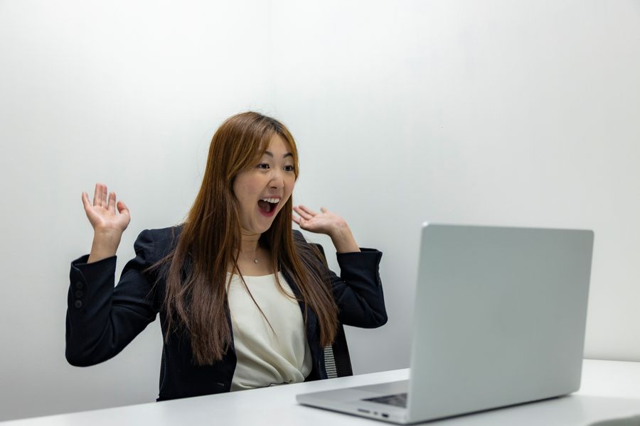 A woman celebrating good news in front of her laptop
